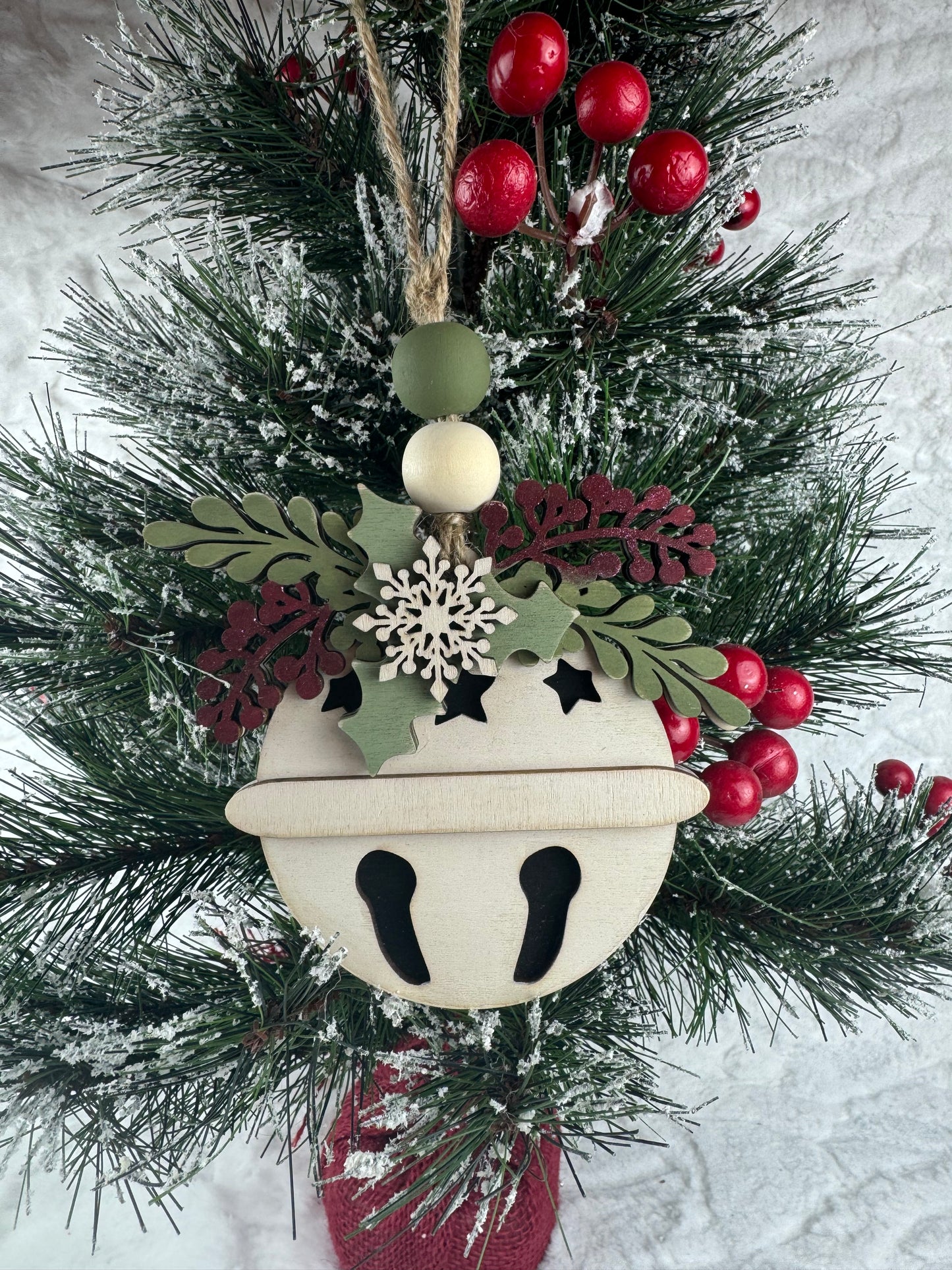 Handcrafted bell ornament with snowflake and greenery on tree