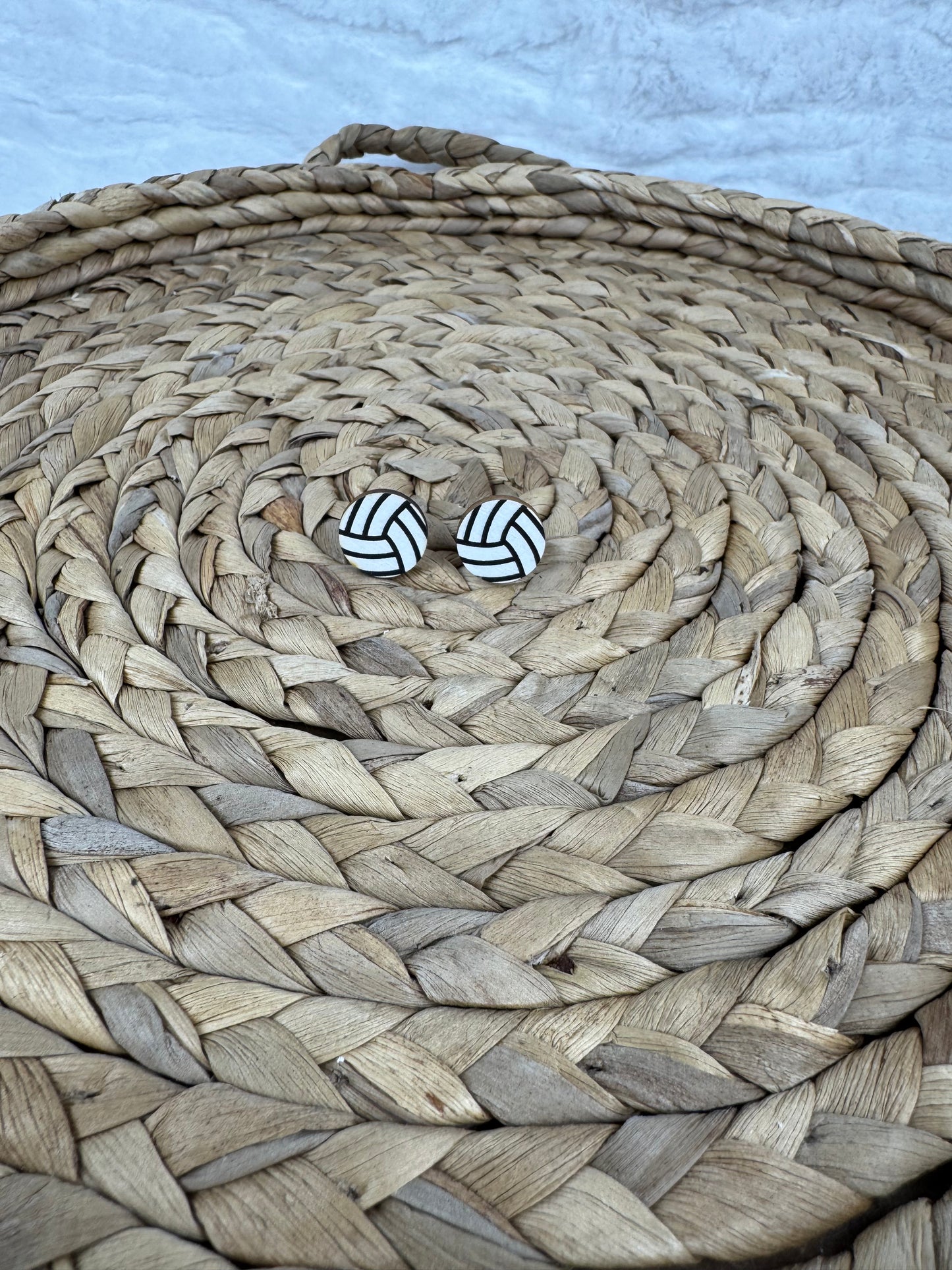 Volleyball studs earrings on woven mat