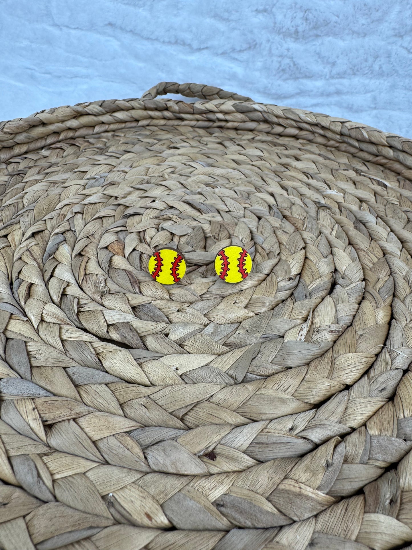 Softball studs earrings on woven mat